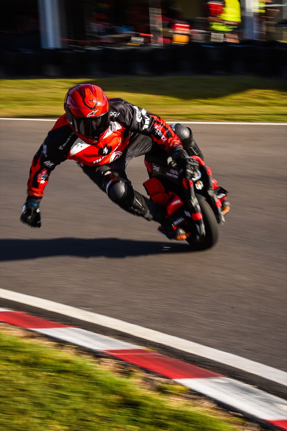 An electric unicycle racer in red leans hard through a corner